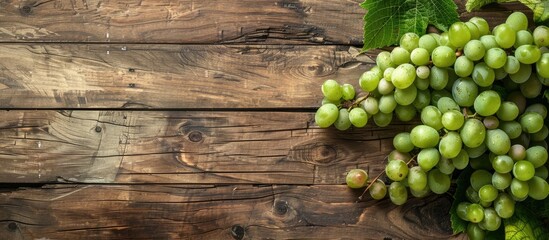 Aufkleber - Fresh green grapes with a bunch and vine leaf displayed on a wooden background in a top view flat lay style with copy space image