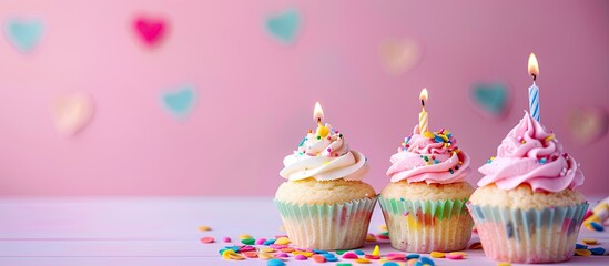 Aufkleber - Pink background with birthday cupcakes featuring lit candles Copy space image available