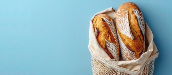 Poster - Flat lay with copy space image of mesh bag holding freshly baked bread on a blue background