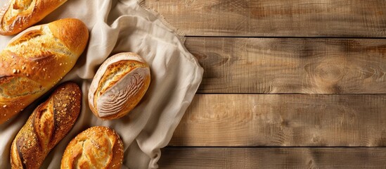 Poster - Various freshly baked breads displayed on a beige kitchen towel against a wooden background captured from above with room for copy space image