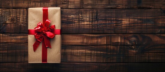 Poster - Wooden backdrop showcasing a gift box tied with a red ribbon viewed from above with ample copy space image