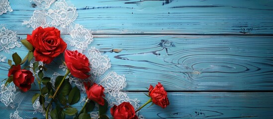 Poster - Top view of red flowers on a lace tablecloth over a blue wooden table with copy space image