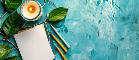 Poster - Top down view on a turquoise textured background with blank notepaper wax pencils and a candle offering ample space for text