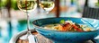 © HN Works - European seafood soup featuring salmon and trout with vegetables served in a vibrant blue dish on a restaurant table paired with a glass of white wine Capture this scene with a copy space image