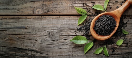 Wall Mural - wooden spoon holding dried black tea leaves displayed on a wooden table with copy space image availa
