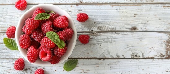 Poster - Fresh red raspberries displayed in a white bowl on a light rustic wood backdrop in a top view image with available copy space and selective focus for a vegetarian context