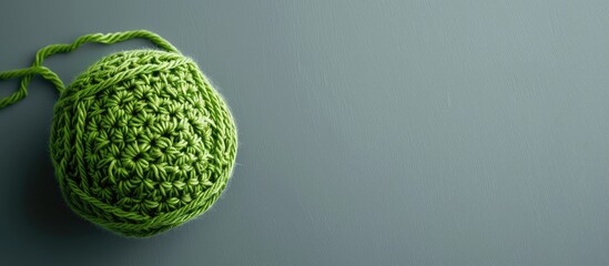 Sticker - Grey backdrop with crocheted pattern and green yarn ball offering copy space image