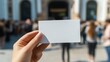 © AI Visual Vault - A hand holds up a pristine white card against a bustling city backdrop, offering a blank canvas for messages, promotions, or announcements.