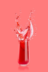 Wall Mural - Red cherry juice in drinking glass with bright splashes, drops flying, swirl on pink background. Organic summer berries beverage with splashing for advertising, design, flyer, card, poster.