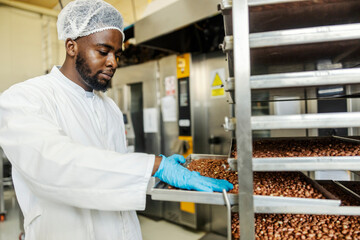 Portrait of multicultural food factory worker baking peanuts and preparing for it for cookies.