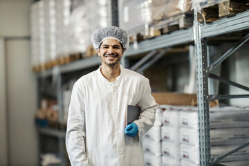 Wall Mural - Portrait of smiling diverse food factory warehouse worker in sterile uniform looking at camera.