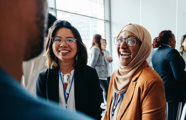 Wall Mural - female colleagues interacting at a corporate workshop with happy smiles and engaging conversations