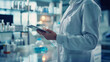 © VK Studio - A laboratory technician in a white coat, focusing on a tablet amidst various scientific instruments and glassware in a modern lab.
