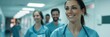 © nopommajun - A group of healthcare professionals in blue scrubs, smiling while walking down a hospital hallway, demonstrating teamwork and positive work environment.