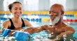 © peopleimages.com - Dumbbell, help and mature man in swimming pool for exercise, healthy body and strong muscle. Aqua therapist, water and aerobics class for fitness, physiotherapy or rehabilitation of senior people