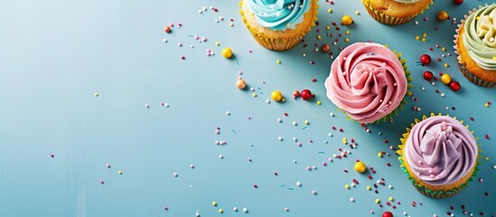 Wall Mural - Birthday party with delicious cupcakes arranged in a flat lay composition on a light blue background ideal for adding text in the copy space image