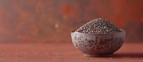 Wall Mural - A small bowl holding chia seeds on a colored surface with copy space image showcasing the nutritious Salvia hispanica seeds a healthy superfood