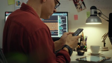 Programming. European guy is attentively immersed in virtual space in the evening room. Cinematic shot of a remote access worker working with a modern smartphone applies new coding methods, data