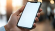 © BOW_NAPASORN - A person is holding a cell phone with a white screen. The phone is in a hand and the person is looking at it
