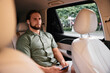 © SHOTPRIME STUDIO - Man sitting in a car using smartphone, wearing earbuds, relaxed expression, casual attire