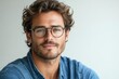 © furyon - charismatic man with tousled hair and designer glasses enigmatic smile crisp blue shirt against pure white backdrop highfashion portrait style