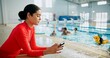 © CineLens2024/peopleimages.com - Children, swimming pool and woman with smartphone, distracted and notification with safety issue and risk. Person, water and kids with coach, typing and lifeguard with internet, danger and caution