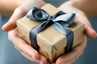 © isti - Hands holding a gift box with a grey ribbon.