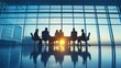© Jenjira - Silhouettes of business professionals in a conference room during sunset, discussing strategies with a panoramic city view.