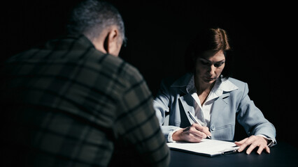 Wall Mural - Woman police officer writing down testimony while listening to a suspect in a crime