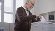 © Synthex🇺🇦 - Elderly man fulfilling his civil duty, throwing a vote ballot into a container