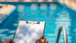 © lenblr - A pool service professional reviews a checklist by the poolside to ensure proper maintenance and safety checks for optimal care and user safety