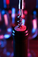 Wall Mural - Wine bottle with corkscrew in lights on blurred background, closeup