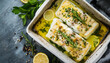 © StellaPattaya - Top view of steamed cod fillet with butter lemon sauce and herbs in a baking dish baked in the oven for a healthy meal