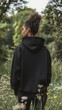 © Philipp - Model showcasing a black hoodie, back view, in a forest. Fashion Mockup Concept.