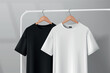 © georgerod - Black and white t-shirts hanging on a clothes rack in a studio on a wooden hanger.