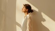 © DreamPointArt - Young woman wearing white shirt enjoying sun rays standing near wall