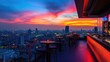 © arthit - Sunset view of Bangkok cityscape from a rooftop bar, highlighting Lumpini area with colorful sky and city lights.
