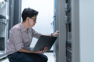 Computer engineer is setting up network in server room,Systems Maintenance Technician,Male engineer working in server room at modern data center