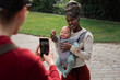 © Milles Studio/Stocksy - Father taking pictures of mother and baby in park