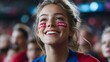 © Stone Story - Excited female sports fan with face paint and French flag at a stadium, cheering for her team during a game.