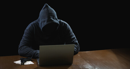 portrait hacker spy man one person in black hoodie sitting on table looking computer laptop used log