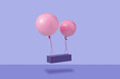 © Yaroslav Danylchenko/Stocksy - Pink gel balloons lifting cargo container over violet surface
