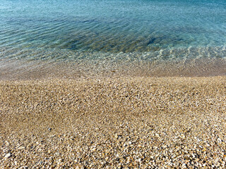 Wall Mural - Beach detail. Sea water touch wet small pebbles, closeup. Summer holiday