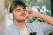 © carballo - young man at home with headphones and mobile phone