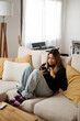 © Felix Chacon/Stocksy - Woman Texting On Sofa