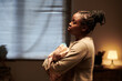 © pressmaster - Side view of young vulnerable and lonely African American woman with newborn baby in hands standing in front of camera at home