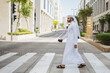 © Daniel Gonzalez/Stocksy - Man Walking Crosswalk in Qatar