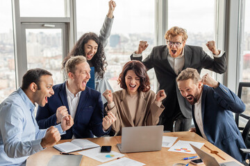 Aufkleber - A group of six colleagues in business attire celebrate a success in a modern office with large windows. They are all excited and raise their fists in the air