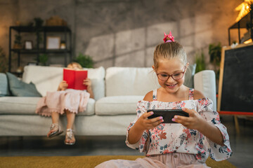 Young caucasian girl sit on floor and use mobile phone at home