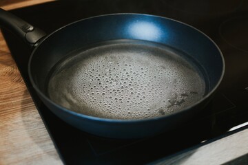 pot with boiling water with bubbles close-up on black kitchen stove